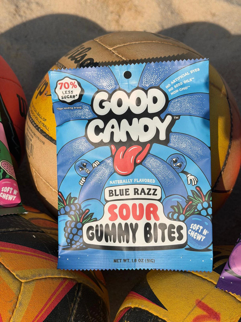 Blue Razz sour gummy bites pouch from Good Candy propped against a worn volleyball.