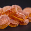 Close-up of Good Candy Watermelon low sugar sour gummies coated in sparkling sugar crystals on a dark background