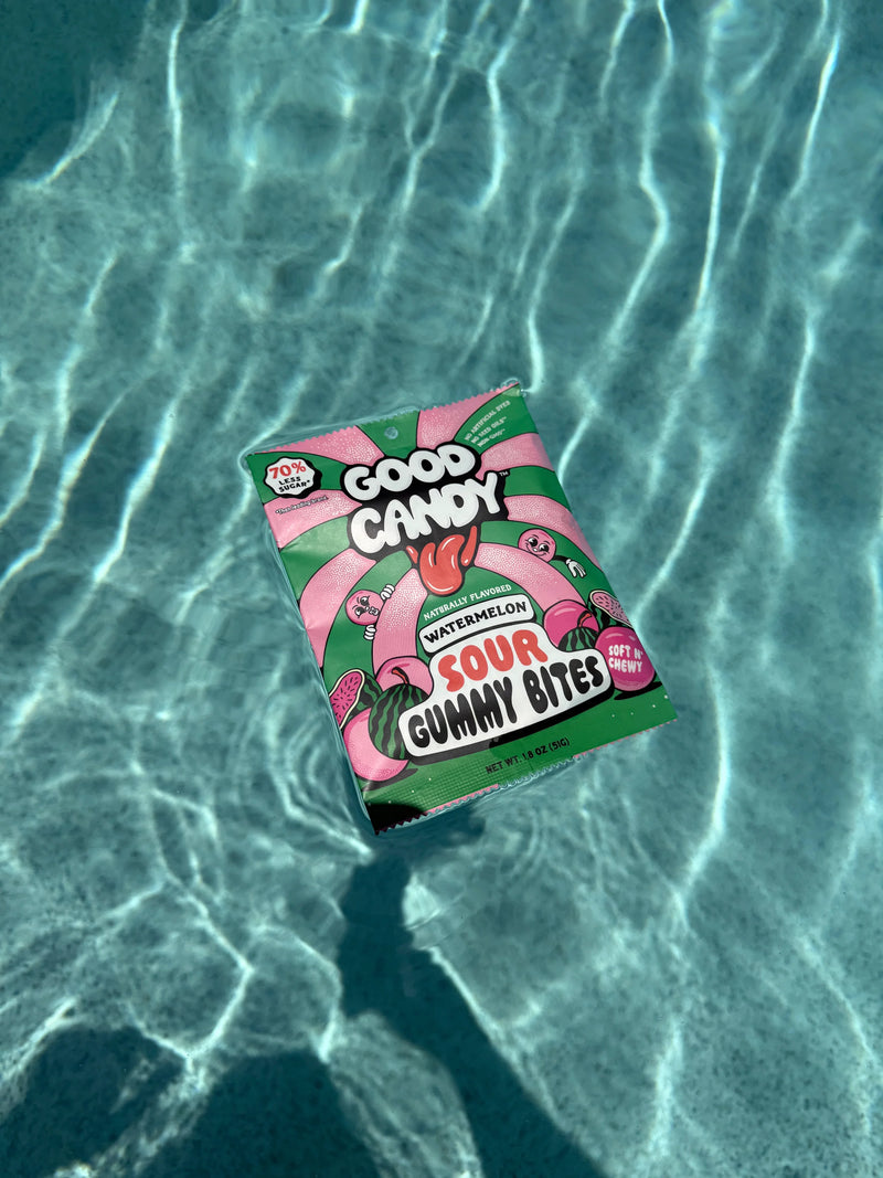 Good Candy watermelon sour gummy bites pouch floating on sunlit turquoise pool water.